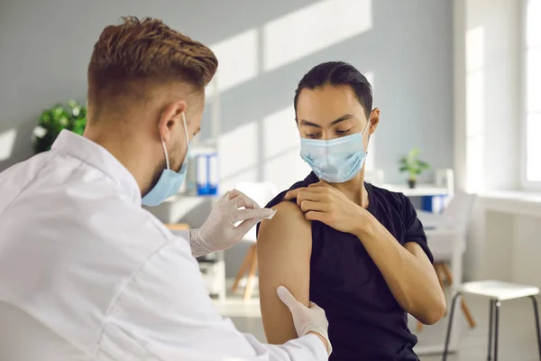 Young man in medical face mask getting seasonal flu shot or modern Covid-19 vaccine — Stock Photo, Image