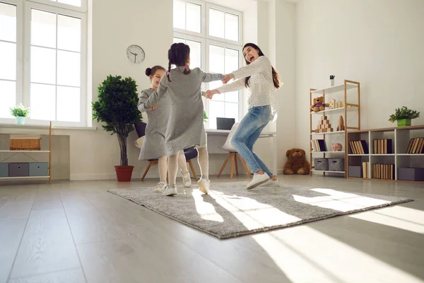 Vrolijke moeder en haar kinderen dansen en lachen in gezellige moderne huiskamer — Stockfoto