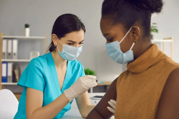 Pielęgniarka w masce medycznej wstrzykująca pacjentowi podczas kampanii szczepień — Zdjęcie stockowe