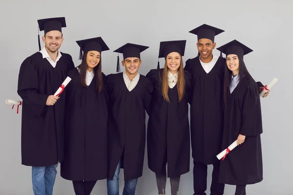 Csoport portré boldog többnemzetiségű egyetemi vagy főiskolai diplomások ölelés és a kamerába nézés — Stock Fotó