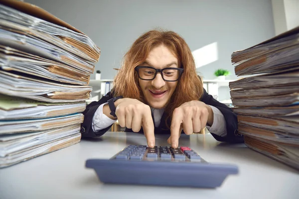 Komik muhasebeci hesap makinesi ve hesaplanan vergi miktarı ile ofis masasında oturuyor. — Stok fotoğraf