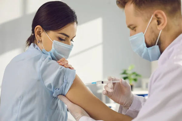 Woman patient giving arm for protection from coronavirus infection and making vaccination — Stock Photo, Image