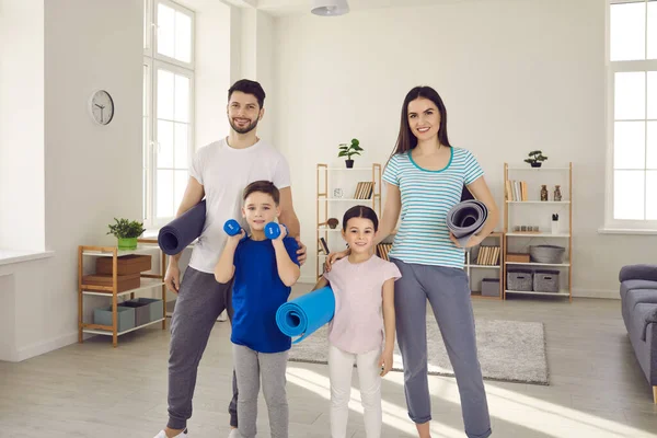 Portret van een jong actief gezin met kinderen die sportmatten vasthouden en naar de camera kijken. — Stockfoto