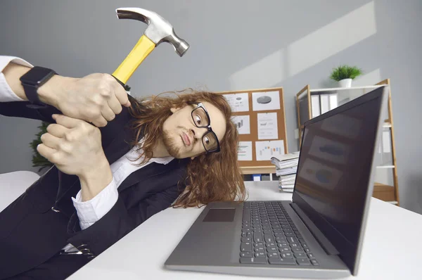 Kızgın ofis çalışanı, arıza ya da veri hatası yüzünden bilgisayarı çekiçle eziyor. — Stok fotoğraf