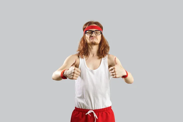 Divertido nerd flaco en ropa deportiva dando un pulgar hacia arriba y motivando a hacer ejercicio —  Fotos de Stock