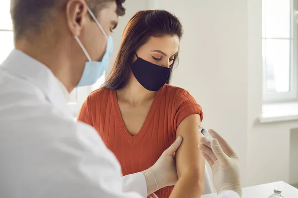 病院での予防接種キャンペーン中に抗ウイルスワクチンを手に入れた顔のマスクの女性 — ストック写真