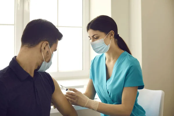 Enfermera o médico profesional inyecta a un paciente con una vacuna contra la gripe o el coronavirus en una clínica moderna. — Foto de Stock