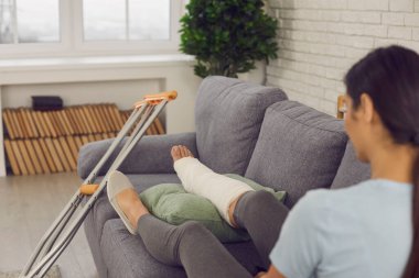 Alçılı bacağı kırık bir hasta koltukta koltuk değnekleriyle oturuyor.