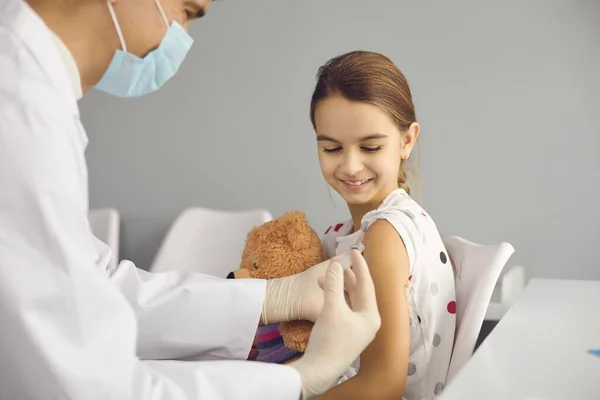 Happy little girl getting a vaccine shot during immunization campaign for children — Zdjęcie stockowe