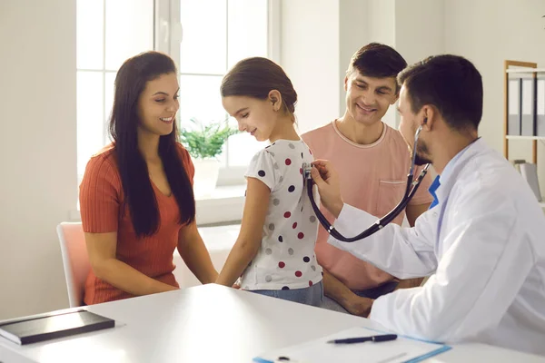 Glückliche Mutter und Vater warten, während der Kinderarzt ihren Töchtern wieder zuhört — Stockfoto