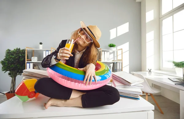 Trabajador de oficina en sombrero de sol, gafas de sol y anillo de natación sentado en el escritorio y soñando con vacaciones —  Fotos de Stock