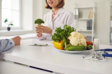 Pozitif kadın doktor beslenme uzmanı erkek hastayla taze vegan sağlıklı beslenmenin faydaları hakkında konuşuyor.