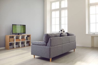 Rahat bir kanepesi ve futbol maçı olan bir televizyonu olan modern oturma odası.