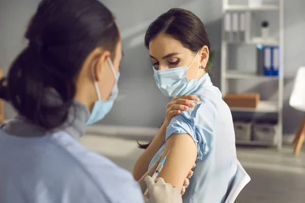 Orvosi maszkban lévő fiatal nő védőoltást kap a fertőzés kitörése alatt — Stock Fotó