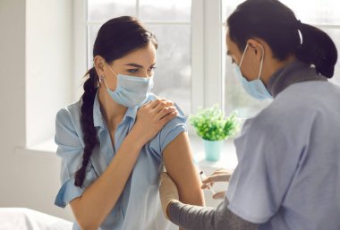 Aşı kampanyası sırasında klinikte ya da hastanede aşı olan genç bir kadın.