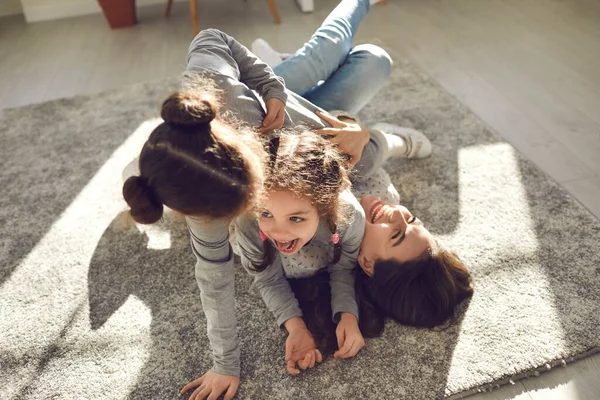 Joyeux jeune mère et petits enfants s'amuser et jouer sur un tapis chaud à la maison — Photo