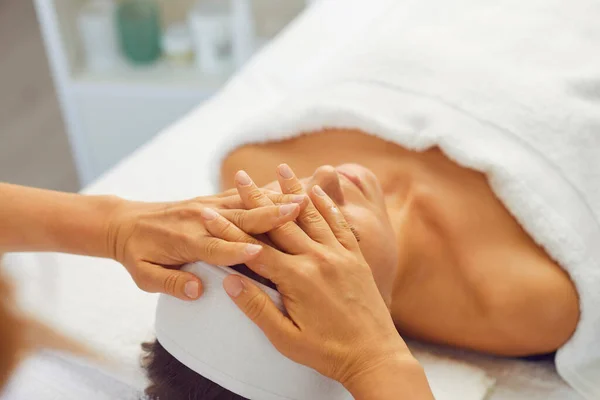 Vrouw het krijgen van professionele face lifting massage tijdens het ontspannen in moderne spa salon — Stockfoto