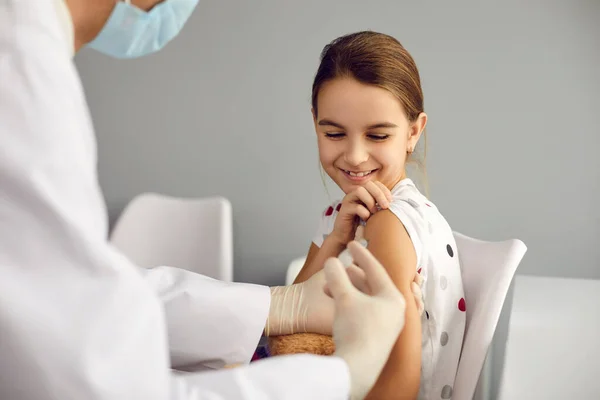 Djärv liten flicka ler får ett skott med ett vaccin mot virussjukdomar. — Stockfoto