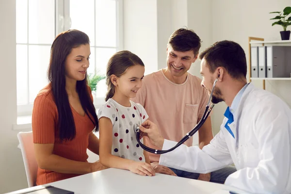 Männlicher Arzt legt ein Stethoskop auf die Brust der kleinen Mädchen und hört auf den Herzschlag und die Lungen. — Stockfoto