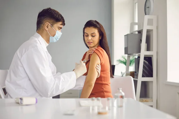 Médico que administra una vacuna a una mujer para la gripe estacional o un brote de una infección. — Foto de Stock