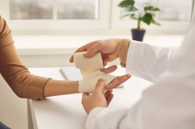 Doktor hastaların ellerini nazikçe geri sarar. Tıbbi ofiste elastik bir bandajla..