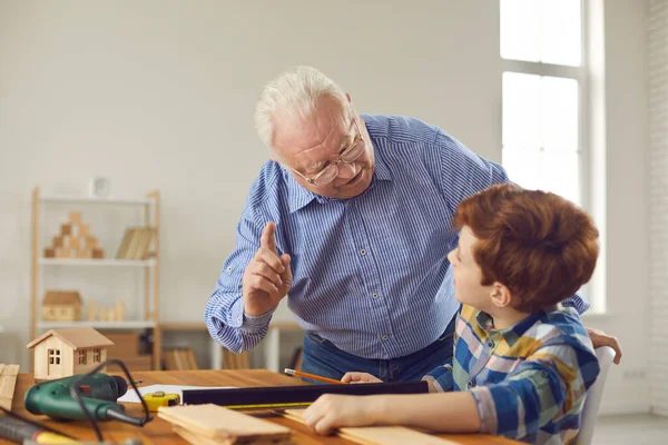 Wijze grootvader herinnert kleinzoon aan veiligheidsmaatregelen bij het werken in de werkplaats — Stockfoto