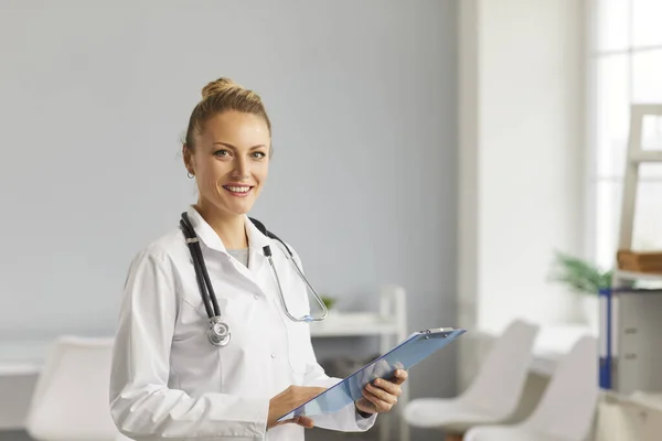 Portret kobiety-lekarza z dokumentami w rękach stojącej w nowoczesnym pokoju szpitalnym. — Zdjęcie stockowe