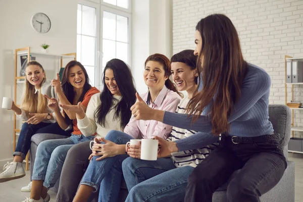 Glada unga kvinnor som sitter i soffan, dricker kaffe, pratar och skrattar — Stockfoto
