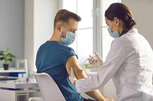 Manlig patient som vaccineras mot injektion från sjuksköterska på kliniken — Stockfoto