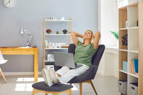 Молода жінка сидить на стільцях в зручному положенні в офісі з ноутбуком і розслабляється — стокове фото