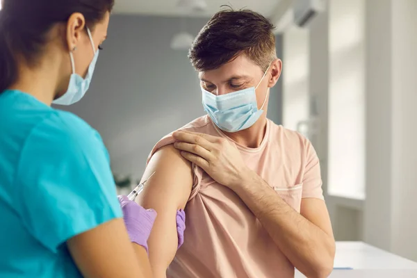 Kvinnlig läkare vaccinerar man patient i armen — Stockfoto