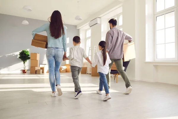 Familia que lleva cajas de cartón y juntos entran en su nueva casa en el día de mudanza — Foto de Stock