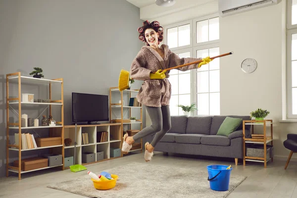 Veselý mladý hospodyňka flákání kolem a baví se při úklidu svého obývacího pokoje — Stock fotografie