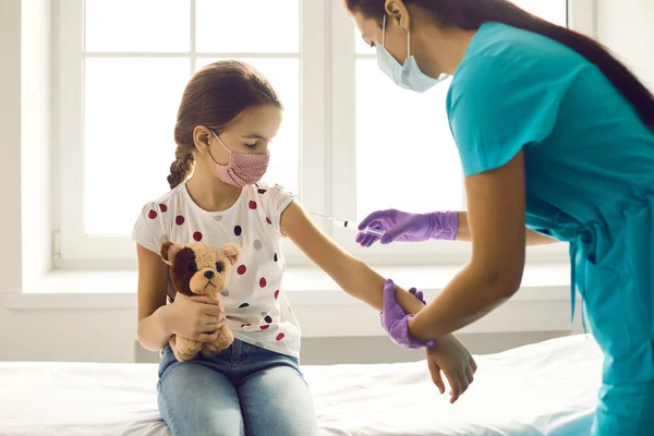 女の子で医療顔マスク見ながら針でザ · インフルエンザショットでザ病院 — ストック写真