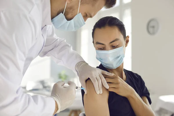 Asiatisk man patient i skyddsmask tittar på läkare man medicinsk arbetare som gör vaccinering injektion — Stockfoto