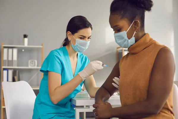 Pracownica medyczna szczepiąca czarną kobietę przeciw kowadłu-19 — Zdjęcie stockowe