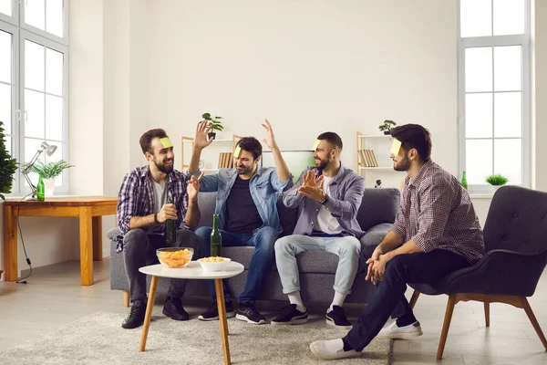 Groep van jonge vrienden hebben plezier en spelen Wie ben ik gokken spel met plakkerige notities — Stockfoto