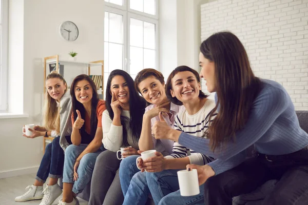 Happy women sitting on couch, drinking coffee, sharing good news and supporting each other — Stock Photo, Image