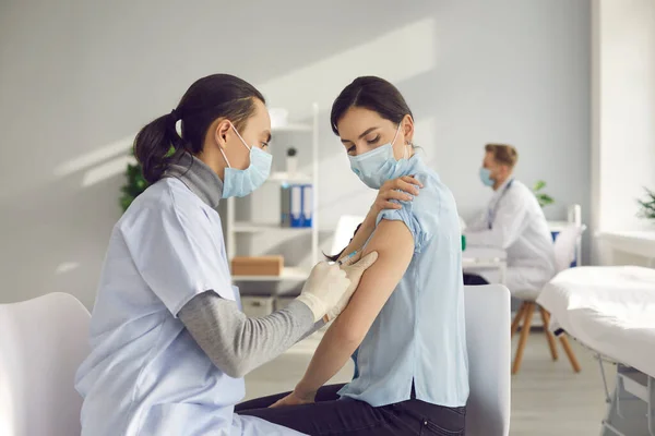 Ung kvinna vaccineras på klinik eller vårdcentral under global Covid-19 pandemi — Stockfoto