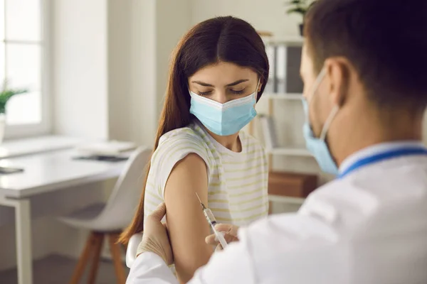 Ung kvinna i ansiktsmask får influensa eller Covid-19 vaccin på kliniken eller sjukhuset — Stockfoto