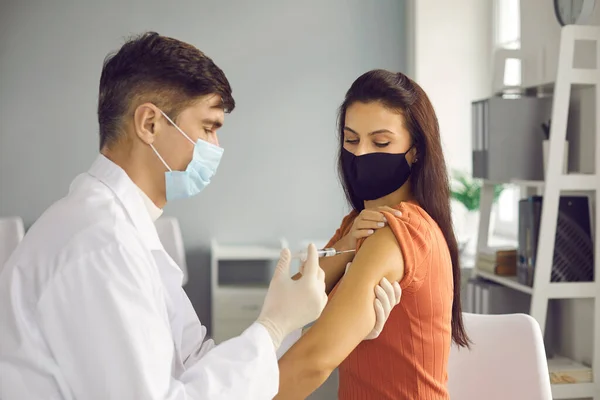 Kvinna i ansiktsmask får influensa eller Covid-19 antiviralt vaccin på läkarmottagningen — Stockfoto