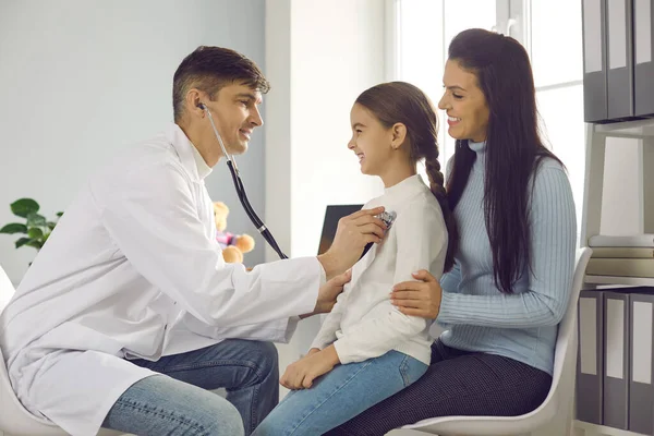 Arzt legt ein Stethoskop an die Brust der Kinder und hört dem Herzschlag und der Lunge der Mädchen zu. — Stockfoto