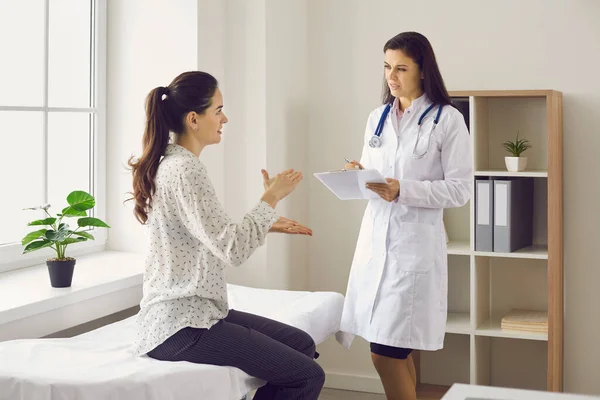 Frau sitzt auf Untersuchungsbett und spricht mit Arzt während ärztlicher Beratung in Klinik — Stockfoto