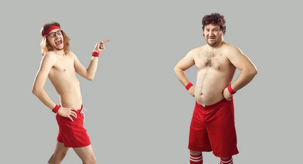 Happy skinny guy laughing at man with some belly fat standing isolated on grey background