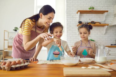 Mutfakta sevgi dolu bir anne, küçük ikiz kızına kek ve kurabiye yapmayı öğretir..