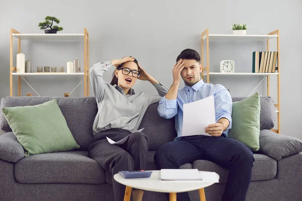 Shocked young married couple looking at notice of bankruptcy or high utility bills