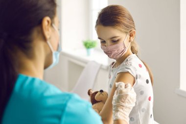 Kadın doktor, kız hastalara aşı yaptıktan sonra kollarını sıvamış.