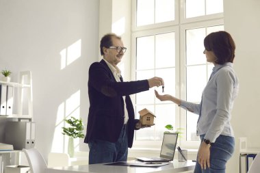 Profesyonel emlakçı ya da emlakçı ev anahtarını mutlu müşterisine verir.