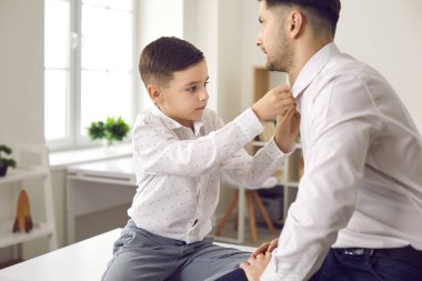 Baba ve küçük oğlu özel bir aile olayı için giyinip beyaz gömlek giyiyorlar.