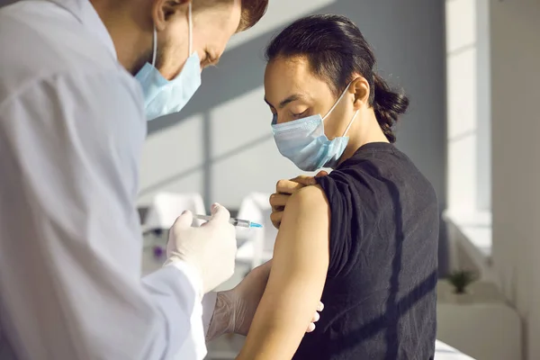 Ung asiatisk man patient ger sin arm till läkare för att göra vaccination — Stockfoto